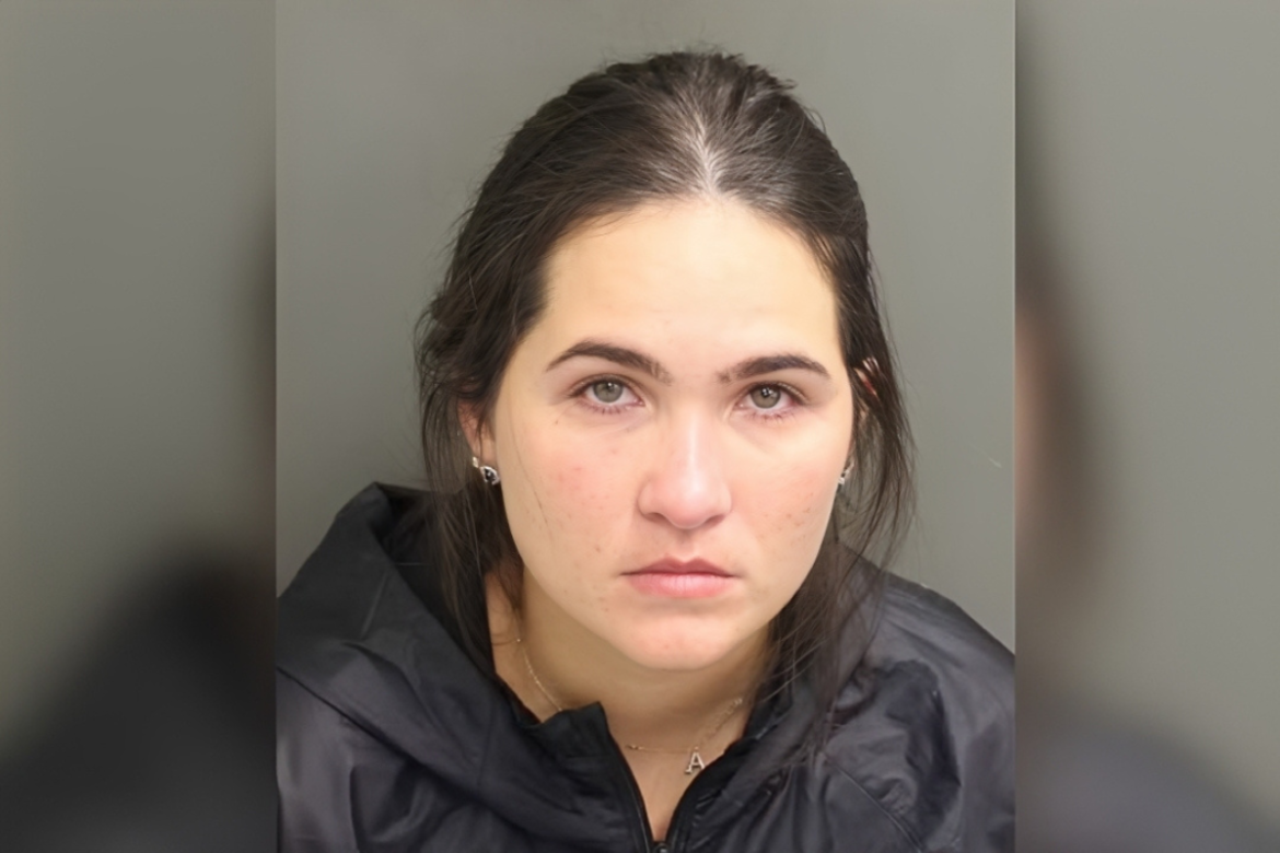 Mulher de cabelos escuros, expressão séria, veste roupa preta e encara a câmera de frente