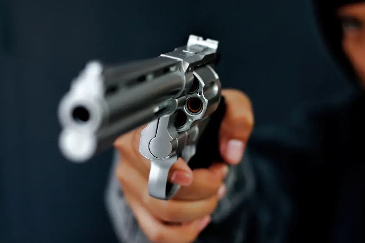 Pessoa encapuzada apontando arma de fogo, representando ataque a tiros que deixou mortos e feridos no Canadá.