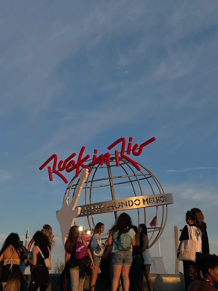 Foo Fighters e Fatboy Slim vão agitar o Rock in Rio 2026; veja detalhes 6 Monumento do globo metálico do Rock in Rio com o letreiro vermelho e a frase "Por um mundo melhor", cercado por fãs sob um céu azul de fim de tarde.