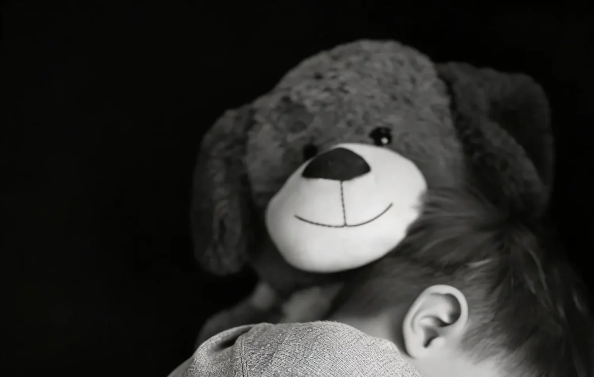 Criança pequena abraçada a um ursinho de pelúcia em imagem simbólica sobre caso de abuso infantil na Bahia.
