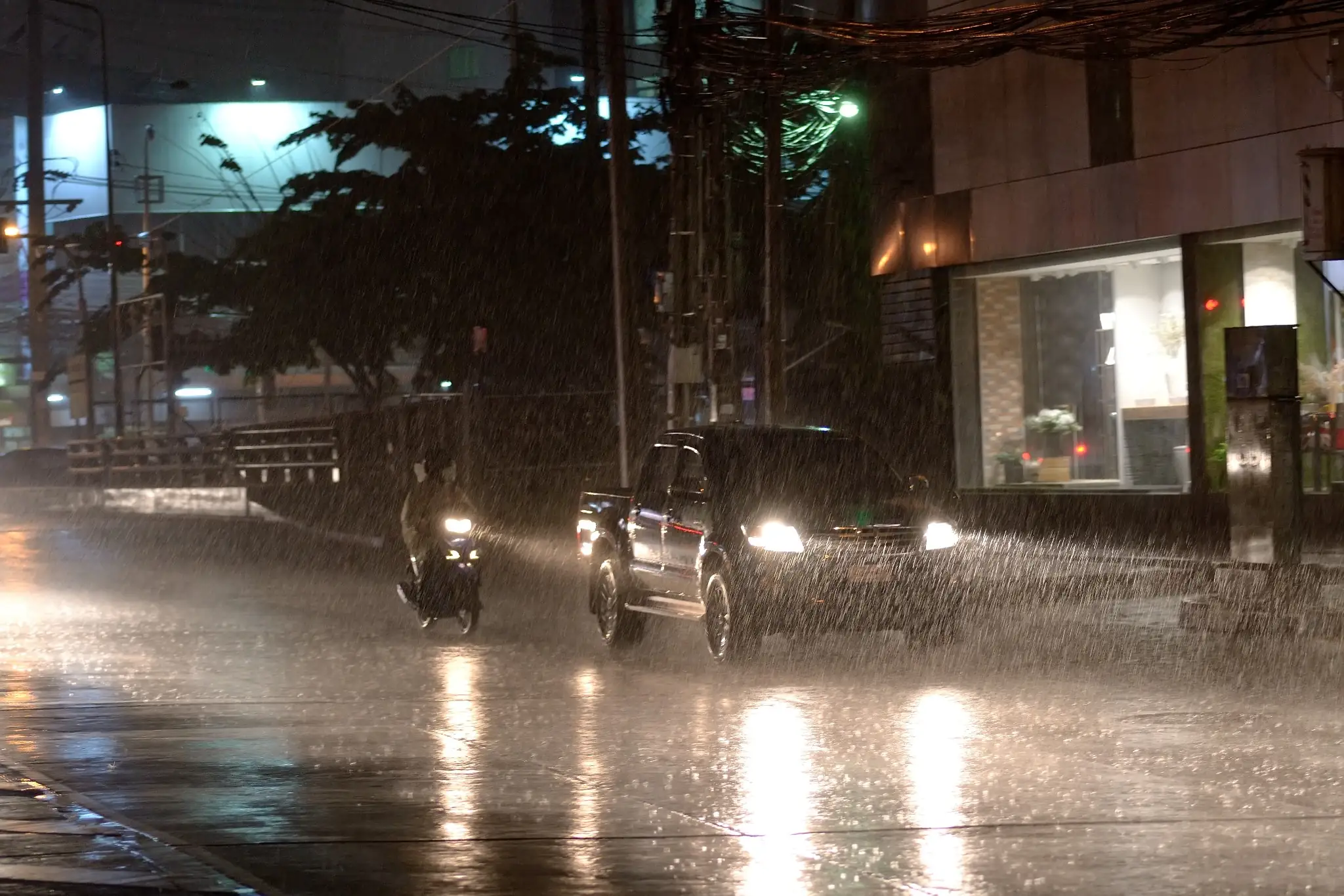 Inmet emite alerta sobre chuva forte ou tempestades durante a semana; confira a previsão 6 Carros e motocicleta circulam sob chuva intensa à noite durante período de instabilidade climática no Brasil.