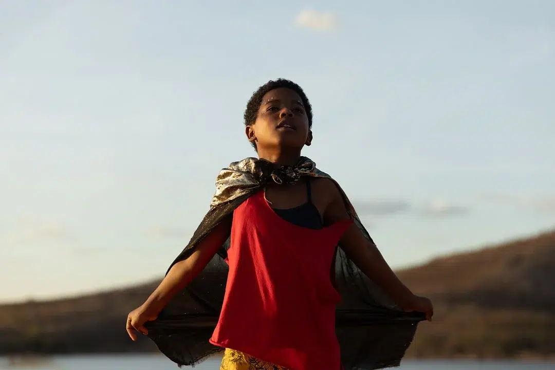 "Feito Pipa" é premiado em Berlim e ganha destaque mundial 6 Menino veste capa dourada e camiseta vermelha, olhando para o horizonte em cenário natural