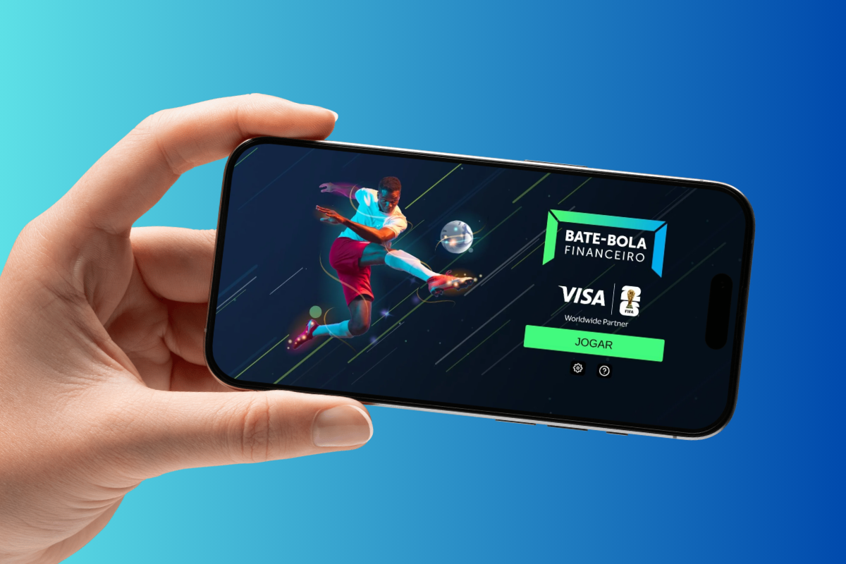 Caixa e MDS lançam microcrédito especial para integrantes do CadÚnico 6 Mão segurando celular exibindo tela inicial do jogo Bate-Bola Financeiro com atleta chutando bola