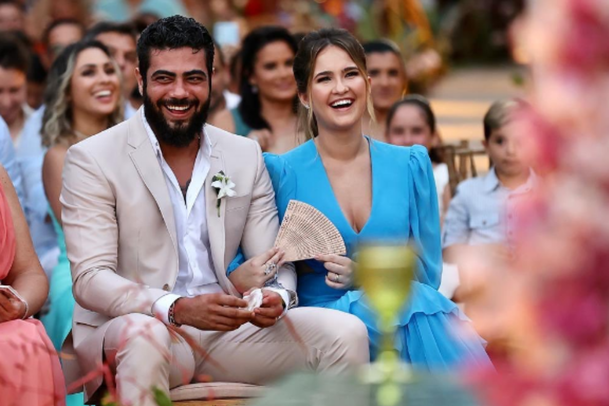 Mulher de Henrique, da dupla com Juliano, é presa nos Estados Unidos 6 Henrique e sua esposa Amanda Vasconcelos sorrindo juntos em evento ao ar livre cercados por convidados