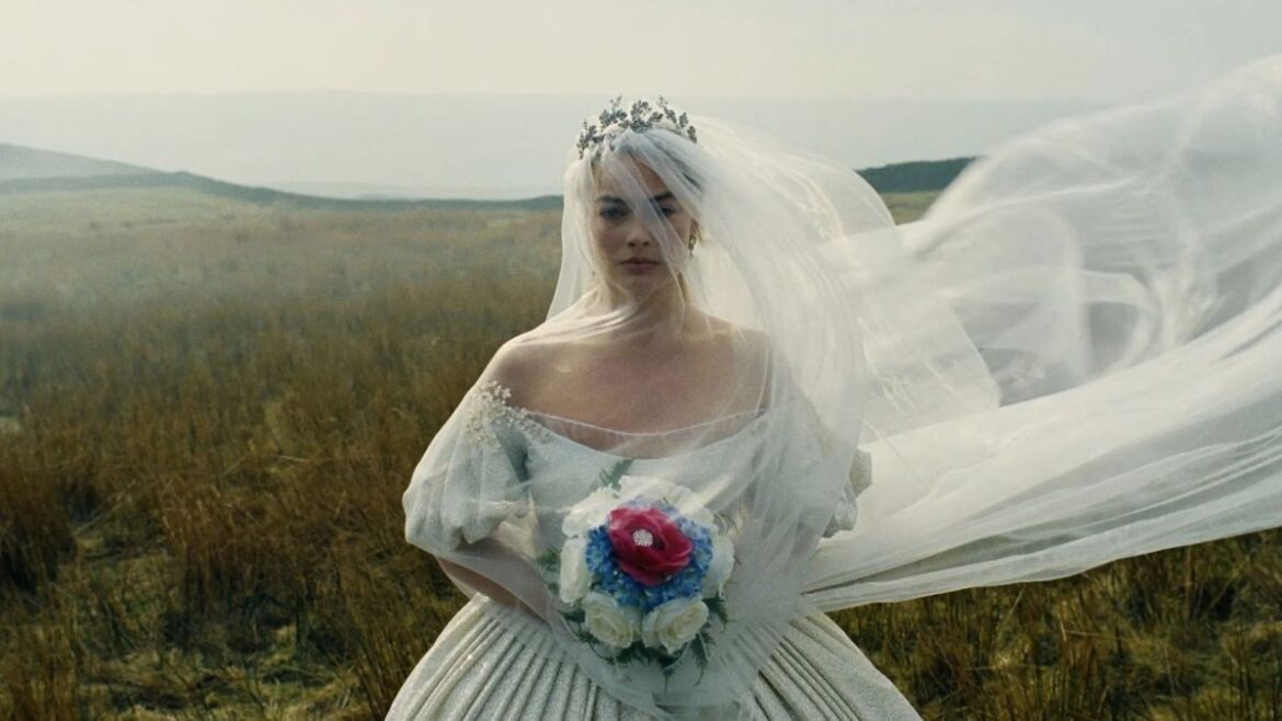 Atriz Margot Robbie caracterizada como Catherine Earnshaw no filme O Morro dos Ventos Uivantes (2026), usando um vestido de noiva clássico com véu longo esvoaçante em um campo aberto e nublado.