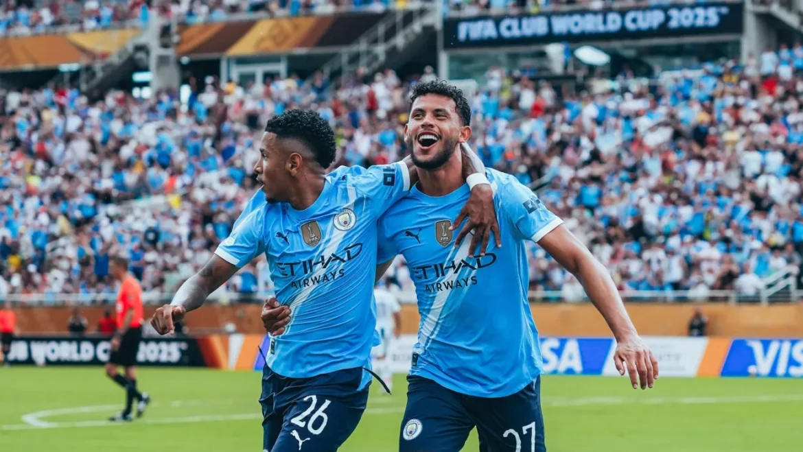 Dois jogadores do Manchester City comemoram gol abraçados em estádio lotado durante partida decisiva da Champions League.