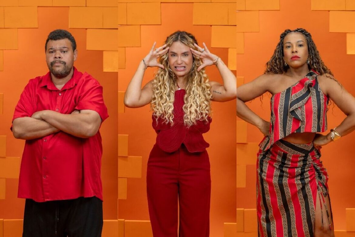 Três pessoas de vermelho posam lado a lado em frente a fundo laranja antes do paredão