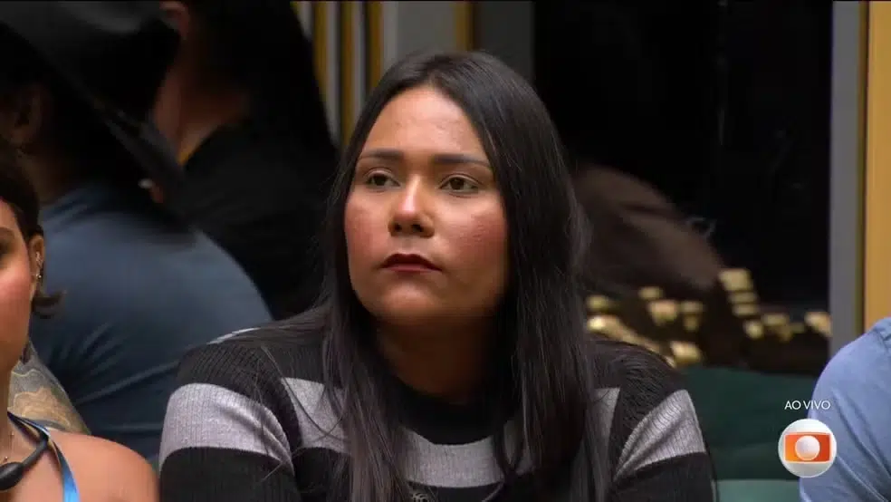 Enquete BBB 26: quem sai no paredão desta semana? Vote e veja parcial atualizada 6 Mulher sentada séria em sala iluminada durante resultado do paredão