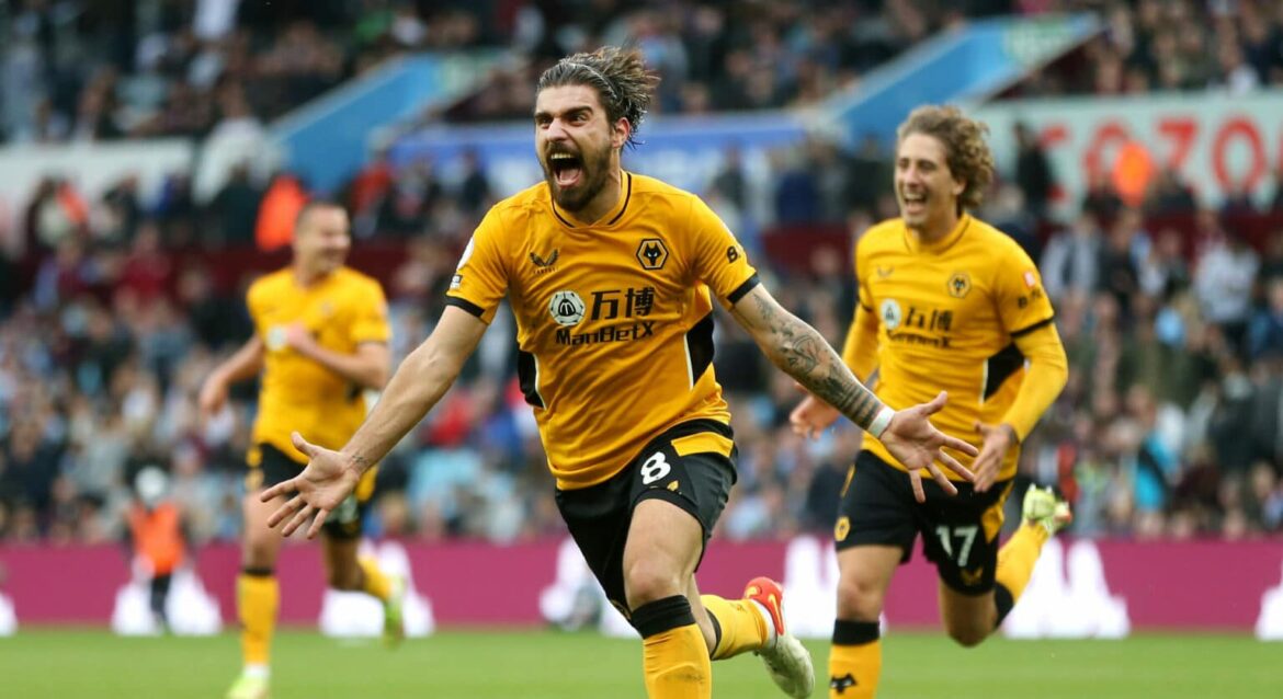 Jogador de futebol com uniforme amarelo vibrando após marcar gol em campo, companheiros ao fundo