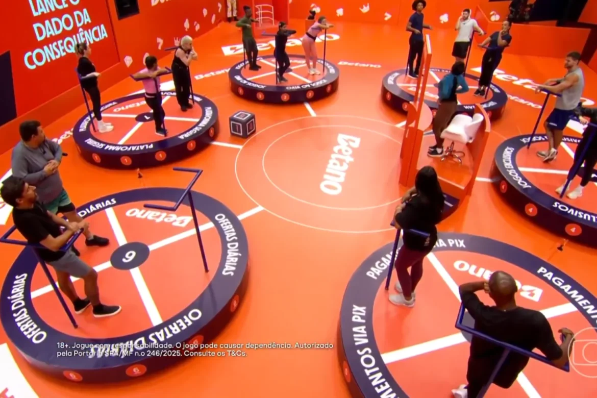 Participantes do BBB 26 em plataformas individuais durante a Prova do Líder de resistência em estúdio cenográfico laranja.