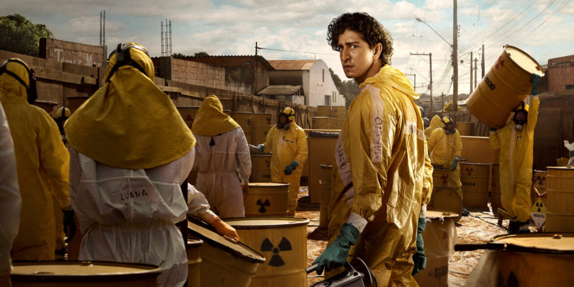 Pessoas com trajes de proteção amarela manuseando tambores de material radioativo em área urbana