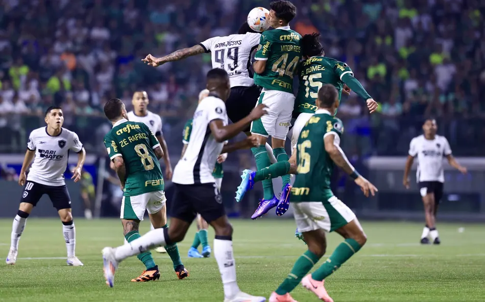 Futebol na Tela: Confira quem joga hoje (18/03) e onde assistir ao vivo pela TV e streaming 6 Atletas saltam para cabecear a bola durante jogo de futebol com torcida ao fundo