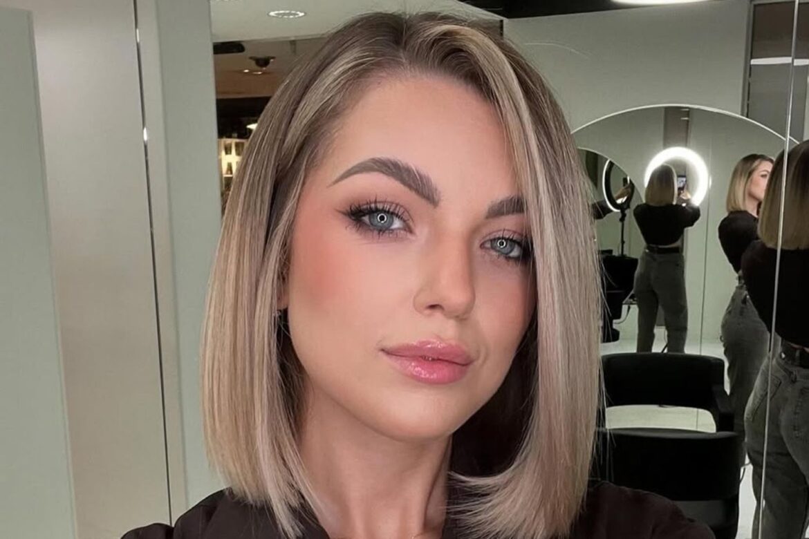 Jovem mulher de cabelos loiros curtos observa a câmera com expressão séria em salão de beleza moderno