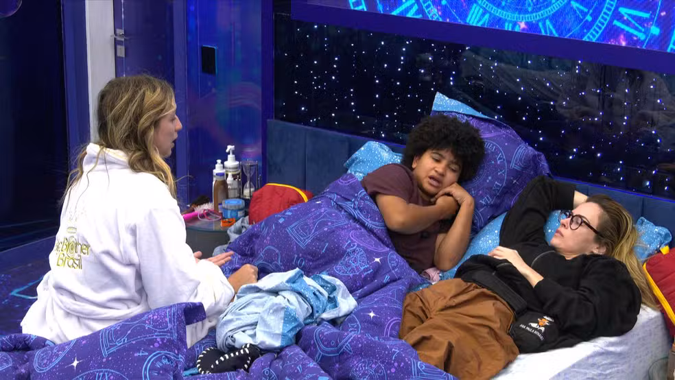 Quarto Secreto do BBB 26: veja os principais momentos de Breno e a chegada emocionante de Juliano 6 Ana Paula Renault, Milena e Samira deitadas no quarto do BBB 26, conversando com expressões sérias e pensativas enquanto especulam sobre o sumiço de Juliano e a dinâmica de Breno.