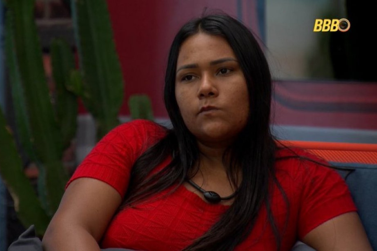 BBB 26: Chaiany revela que usava drogas no passado e justifica apagões no programa 6 Mulher sentada de camiseta vermelha com expressão séria em ambiente do BBB 26