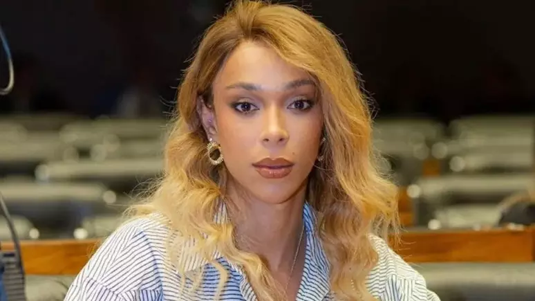 Erika Hilton processa Ratinho por transfobia e pede milhões em indenização 6 Mulher de cabelos loiros sentada em plenário, expressão séria e atenta