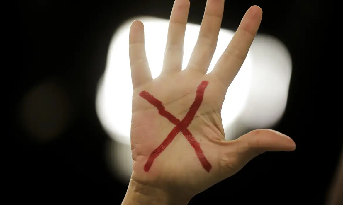 Homem é investigado por importunação sexual contra adolescente de 14 anos em Sorocaba (SP); veja o vídeo 6 Homem investigado por importunação sexual em Sorocaba — mão erguida com um X vermelho pintado na palma, simbolizando recusa e combate à violência sexual