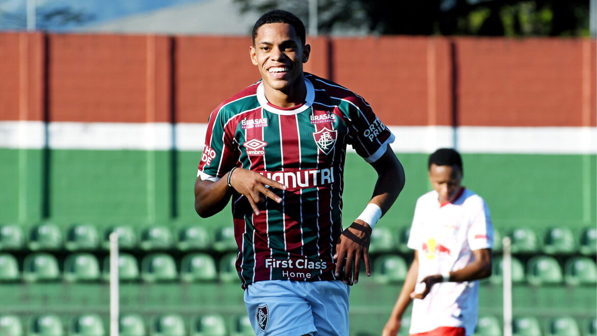 Atacante do Fluminense sorri e faz gesto com as mãos após marcar gol em campo com arquibancadas vazias ao fundo