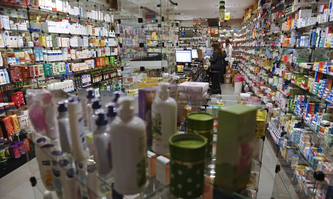 Câmara aprova venda de medicamentos em supermercados; entenda como vai funcionar 6 Câmara aprova venda de medicamentos em supermercados — farmácia com prateleiras de remédios e atendente no balcão representa o modelo que poderá funcionar dentro dos supermercados