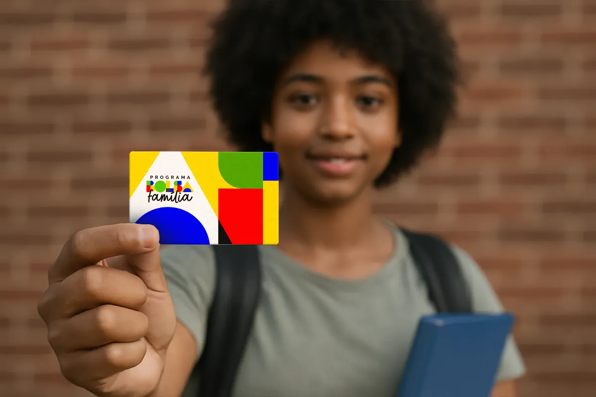 Bolsa Família março 2026: pagamentos começam nesta quarta; confira calendário 6 Jovem segurando cartão colorido do Bolsa Família com livro azul nas mãos