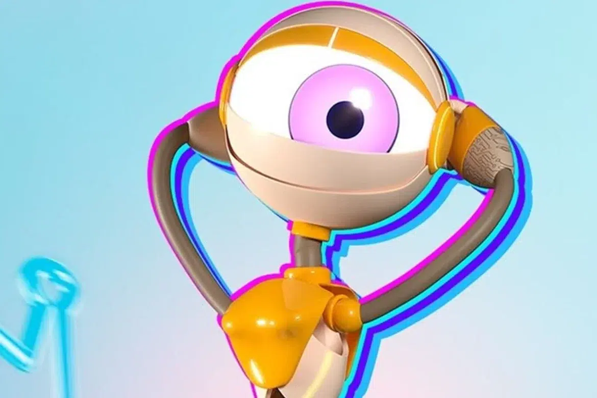 Close no mascote do BBB, um robô branco com um grande olho rosa, em pose de comemoração com as mãos nas "orelhas" amarelas, contra um fundo azul claro com contornos de neon neon.