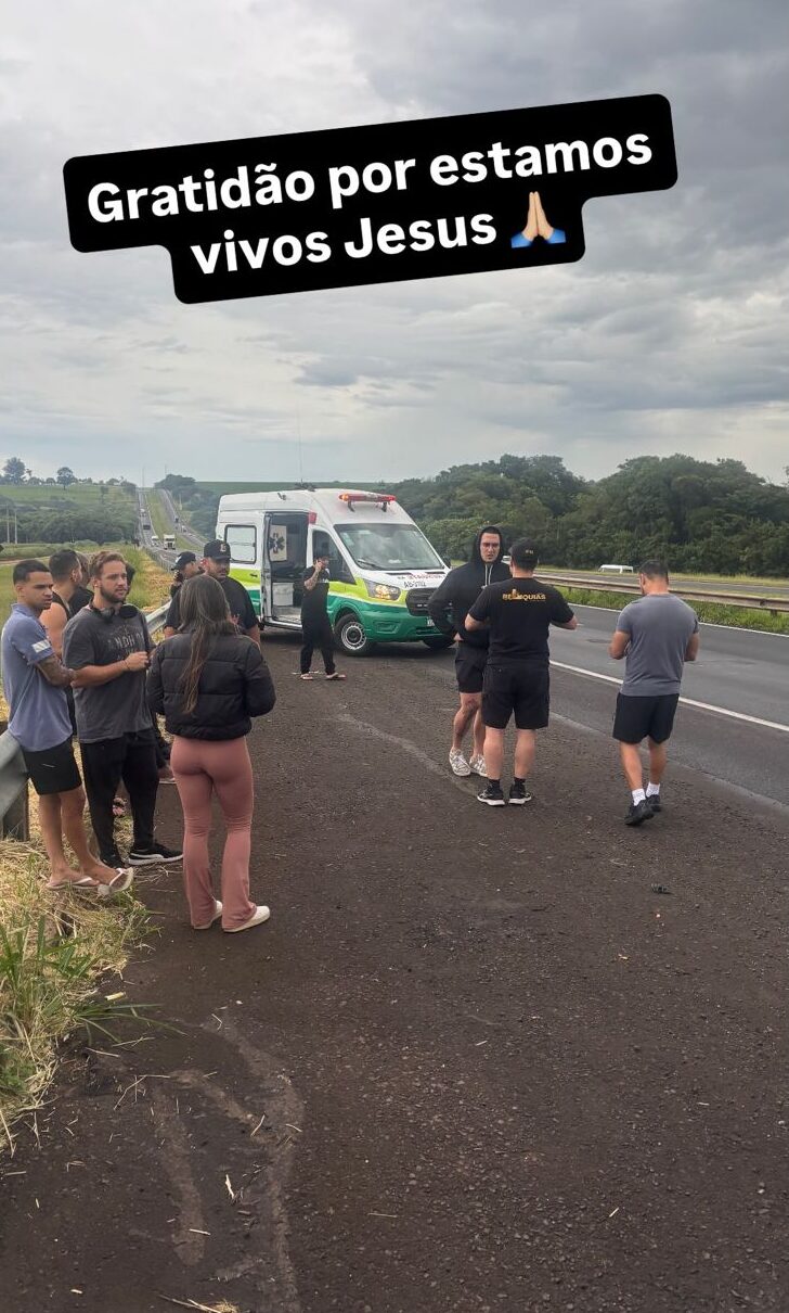 Cantor Latino e equipe sofrem acidente de ônibus em rodovia de SP; veja os detalhes divulgados 6 Grupo de pessoas ao lado de ambulância parada em rodovia sob céu nublado