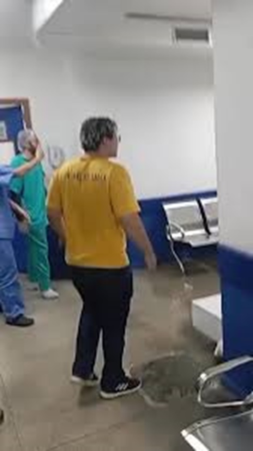 Após perder a mãe, homem se desespera e depreda CRAS; assista ao vídeo 6 Homem de camisa amarela em pé observa funcionária de roupa verde enquanto objetos caídos ficam espalhados pelo chão do CRAS