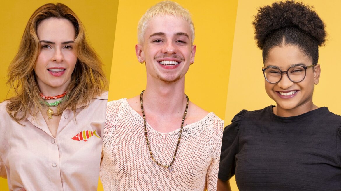 Ana Paula Renault, Juliano Floss e Milena sorrindo lado a lado em fundo amarelo como finalistas do BBB 26