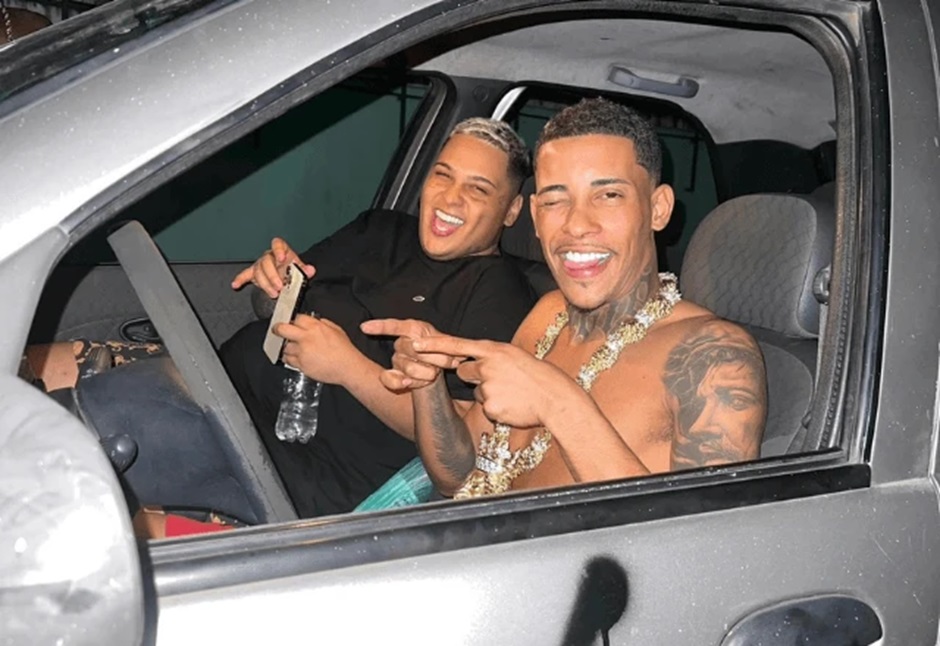Dono da Choquei é preso em operação que deteve MC Ryan e MC Poze do Rodo 6 MC Ryan SP, com tatuagem no braço e corrente dourada, sorri ao lado de amigo em carro prateado à noite