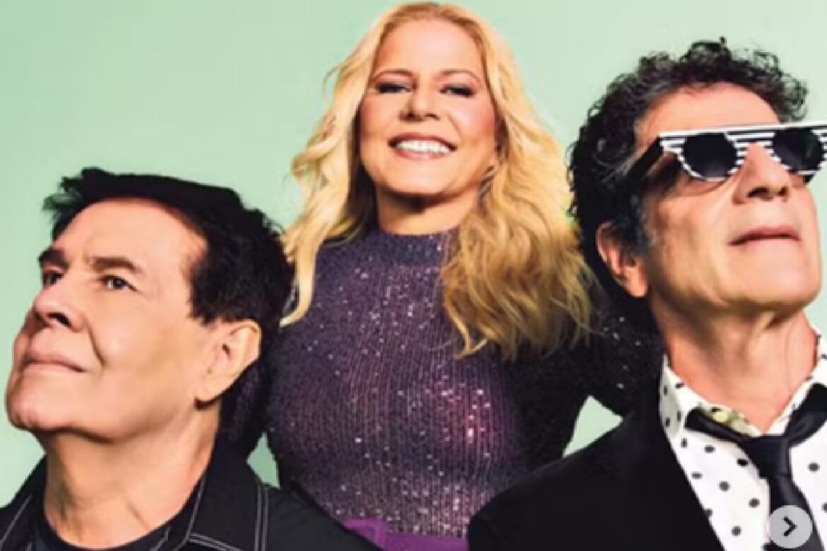 Paula Toller de vestido roxo brilhante ao centro, George Israel à esquerda e Bruno Fortunato de óculos à direita