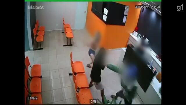 Mulher impede roubo durante assalto em clínica médica; assista 6 Mulher enfrentando homem de capuz verde durante tentativa de assalto em clínica com cadeiras laranjas