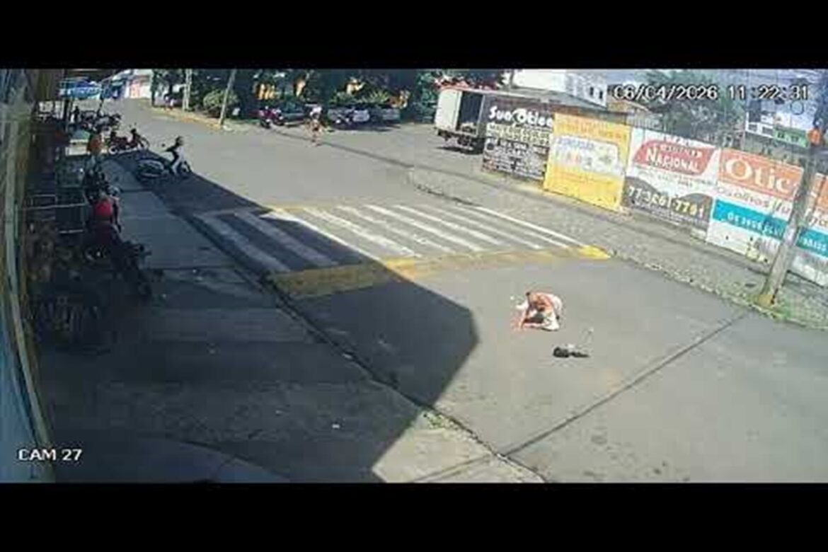 Senhora caída no asfalto após atropelamento na faixa de pedestres no bairro Nova Itapetinga, com moto ao fundo