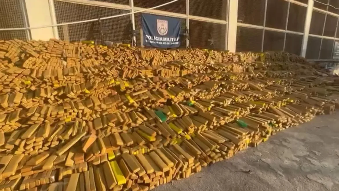 Milhares de tabletes de maconha empilhados em galpão com bandeira da PM do Rio ao fundo