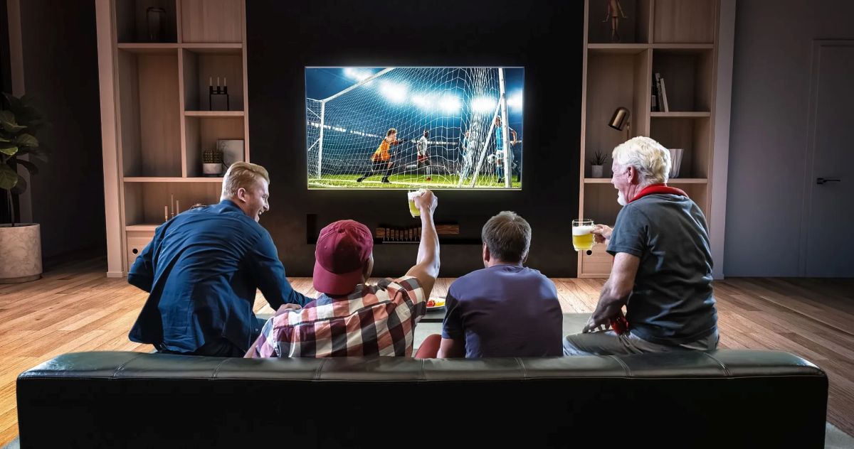 Copa do Mundo terá TV 3.0; veja as novidades que a tecnologia deve trazer 6 Grupo de amigos comemorando gol enquanto assistem futebol em TV com recursos digitais avançados.