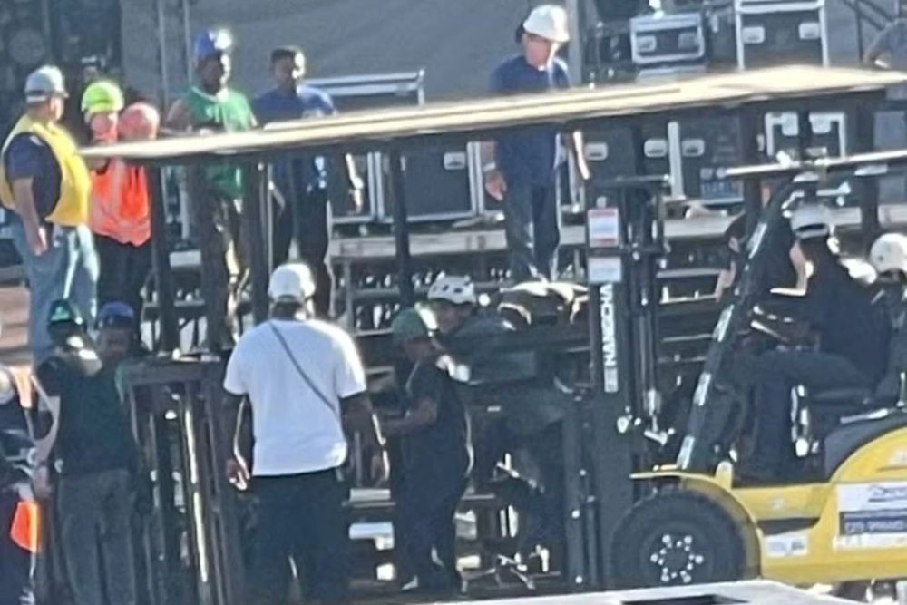 Tragédia em Copacabana: acidente mata funcionário na montagem do show da Shakira 6 Operários utilizam empilhadeira amarela e maquinário hidráulico para retirar colega das ferragens durante acidente na montagem de palco em Copacabana.