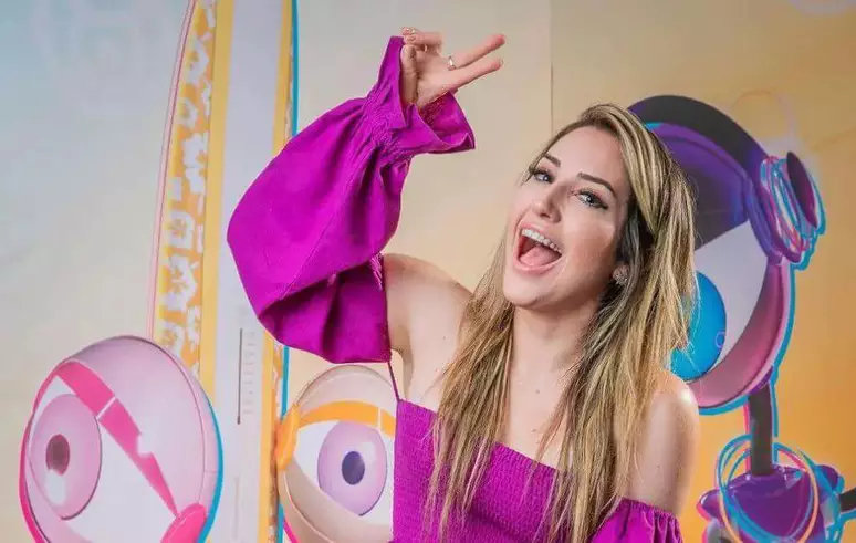 BBB: saiba o que vencedores de outras edições fizeram com o dinheiro do prémio 6 Ex-BBB Amanda Meirelles sorrindo e fazendo o sinal de "paz e amor", em ambiente de estúdio decorado com robôs (dummies) do Big Brother Brasil, ilustrando os benefícios de se planejar financeiramente após vencer o reality.