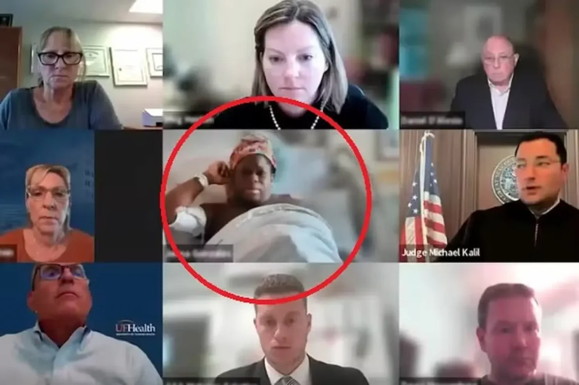 Mulher em trabalho de parto participando de videoconferência enquanto está em cama hospitalar, com médicos e juiz envolvidos no processo.