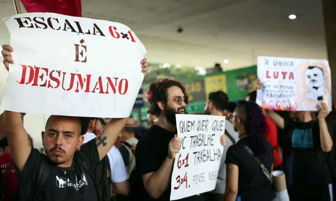 Manifestantes em um protesto segurando cartazes contra a escala 6x1. Um dos cartazes diz 'Escala 6x1 é desumano', ilustrando o debate sobre o fim da jornada de trabalho seis por um no Brasil.
