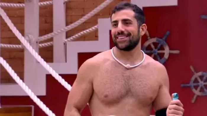 Além de Ana Paula Renault: Relembre outros participantes que perderam parentes durante o BBB 7 Kaysar Dadour sorrindo durante o confinamento do BBB 18, representando a superação e a resiliência emocional diante da distância da família na Síria.