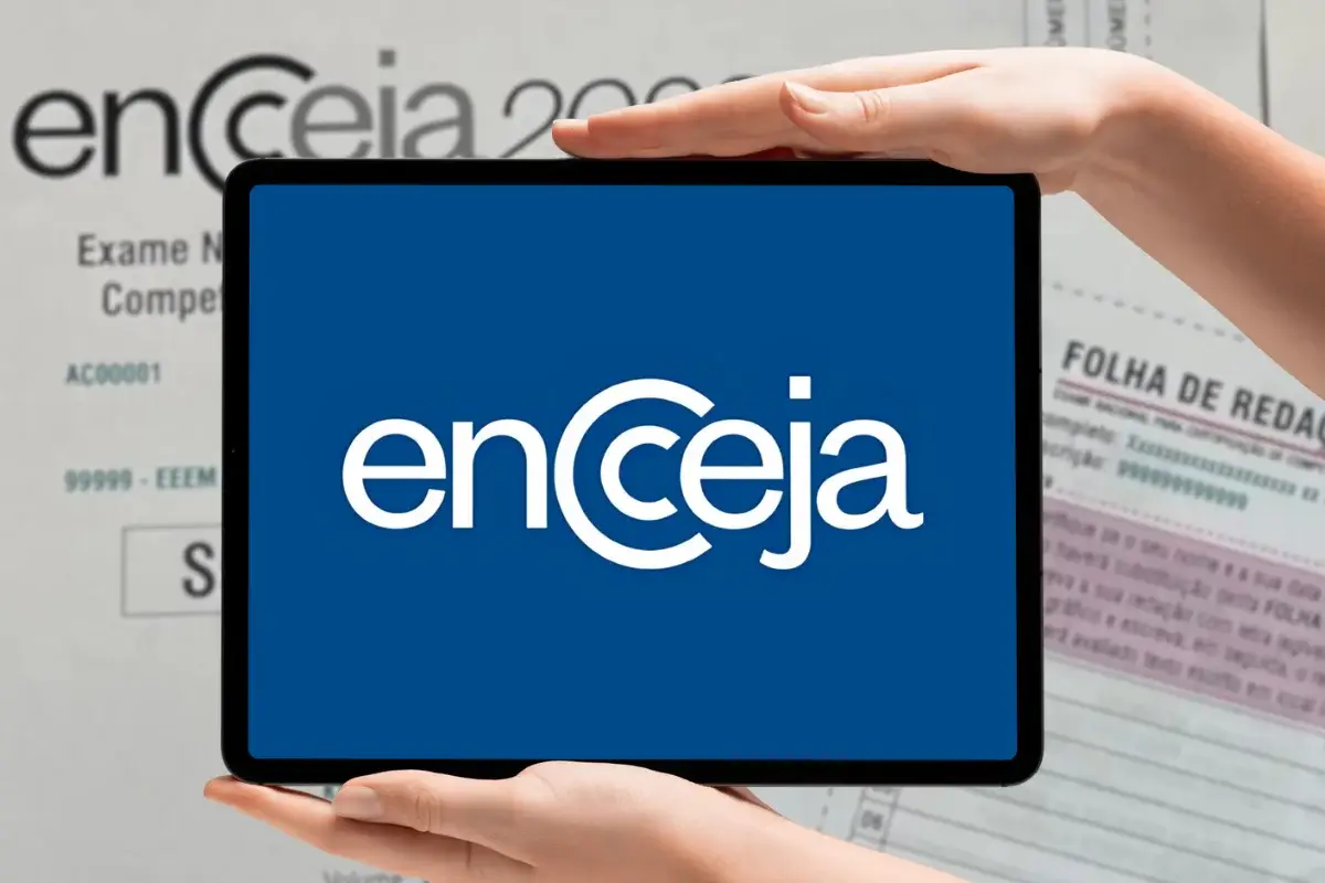 Encceja 2026: peça isenção da taxa de inscrição até o dia 17; veja como fazer 6 Mãos segurando um tablet que exibe o logotipo branco do Encceja sobre um fundo azul; ao fundo, desfocado, vê-se uma folha de redação oficial.