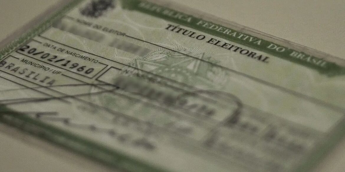 Close de um Título de Eleitor brasileiro antigo (modelo de papel verde). A imagem está com foco seletivo, mostrando detalhes do documento sobre uma superfície clara. O topo do documento exibe "Justiça Eleitoral" e "República Federativa do Brasil".