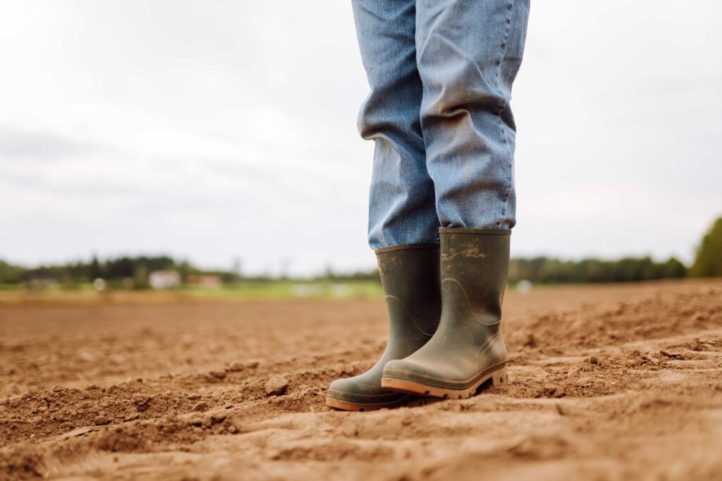 Amado Batista e BYD aparecem em "lista suja" do trabalho escravo 6 Pernas com calça jeans e botas de borracha verde em solo de terra preparado para plantio em área rural