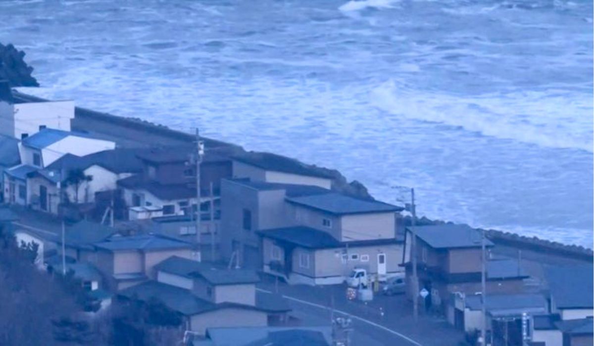 Japão sofre forte terremoto e alerta para tsunami é disparado; veja imagens 6 Vista aérea de uma vila costeira no Japão com ondas do mar agitadas ao fundo, ilustrando a evacuação e os impactos imediatos do terremoto e alerta de tsunami de abril de 2026.