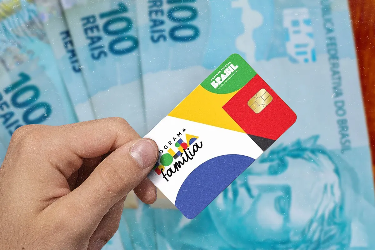 Caixa começa a liberar Bolsa Família de maio: famílias com crianças de até 6 anos recebem R$ 150 extras 6 Mão segurando cartão do Programa Bolsa Família com chip dourado sobre notas de R$ 100 azuis do Governo Federal