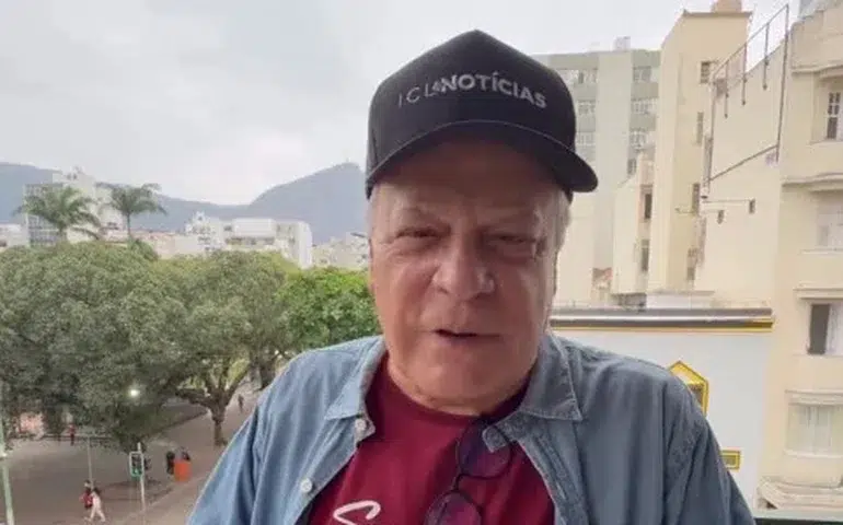 Chico Pinheiro revela diagnóstico de câncer no intestino e relata internação após complicações 6 Chico Pinheiro, 72 anos, usando boné do ICL Notícias, camisa azul sobre camiseta vinho, em varanda com prédios ao fundo