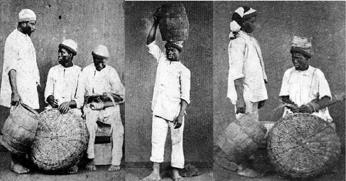 Homens negros escravizados com cestos de palha e turbantes brancos em fotografia de estúdio do século XIX