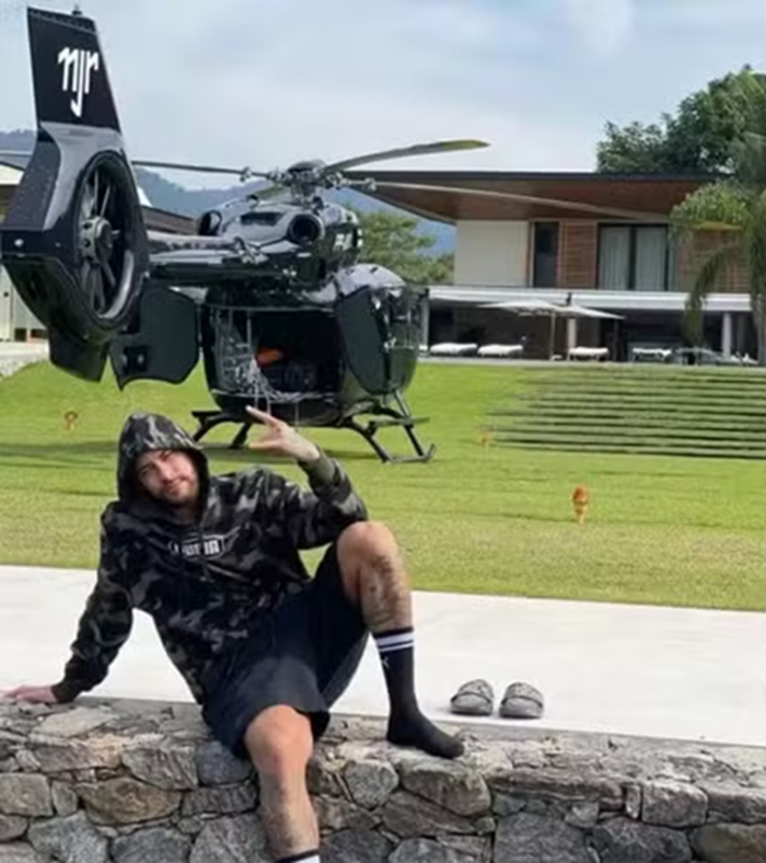 CBF freta helicópteros para levar jogadores convocados para a Copa à Granja Comary: Neymar, Alisson, Endrick e mais 9 já desembarcaram nesta quarta (27/05) 6 Neymar sentado no gramado usando moletom camuflado com helicóptero preto com iniciais NJR ao fundo