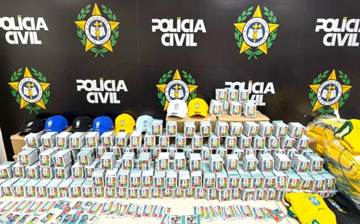 Figurinhas falsificadas do álbum da Copa do Mundo de 2026 apreendidas em Nova Iguaçu, exibidas com bonés e camisas da seleção brasileira