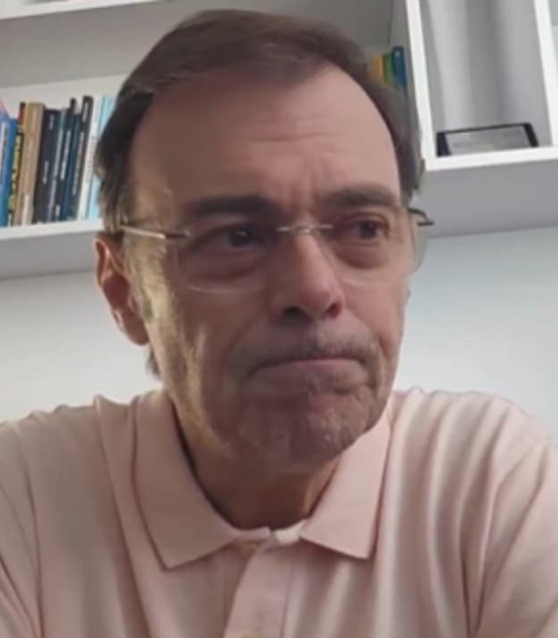 "Estou precisando trabalhar": Tino Marcos viraliza e revela que vídeo era pegadinha para anunciar Copa no Porta dos Fundos 6 Tino Marcos, 64 anos, de óculos e camisa rosa clara, em ambiente doméstico com estante de livros ao fundo