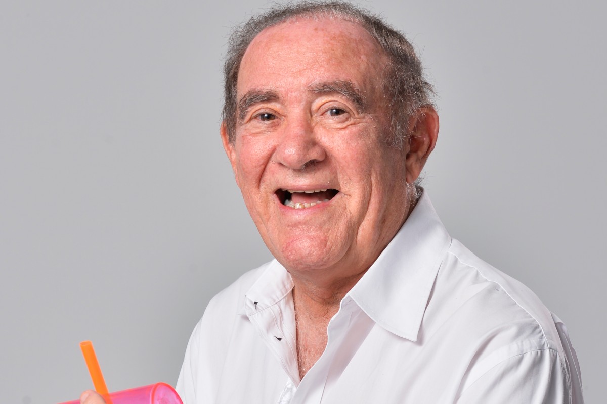 Mansão de Renato Aragão pode ser bloqueada por dívida de IPTU 6 Humorista Renato Aragão sorrindo, vestindo camisa branca e segurando copo rosa com canudo laranja